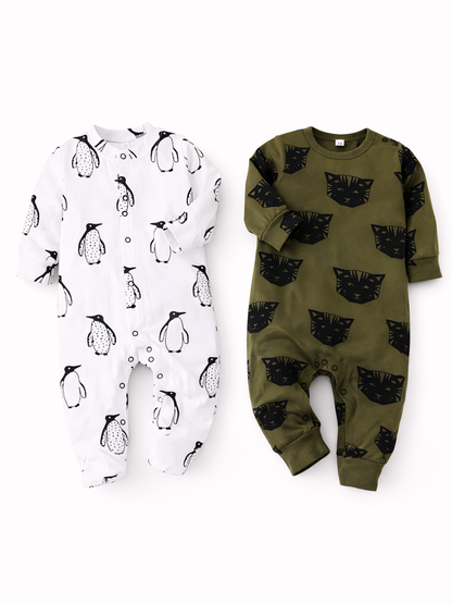 白背景に、ベビー用の長袖ロンパースが2着並んでいる。左は白地にペンギン柄の足つきロンパース、右はカーキ地に黒いネコの顔柄の足なしロンパース。やわらかな影がつき、縫製や生地の質感がはっきり見える。

