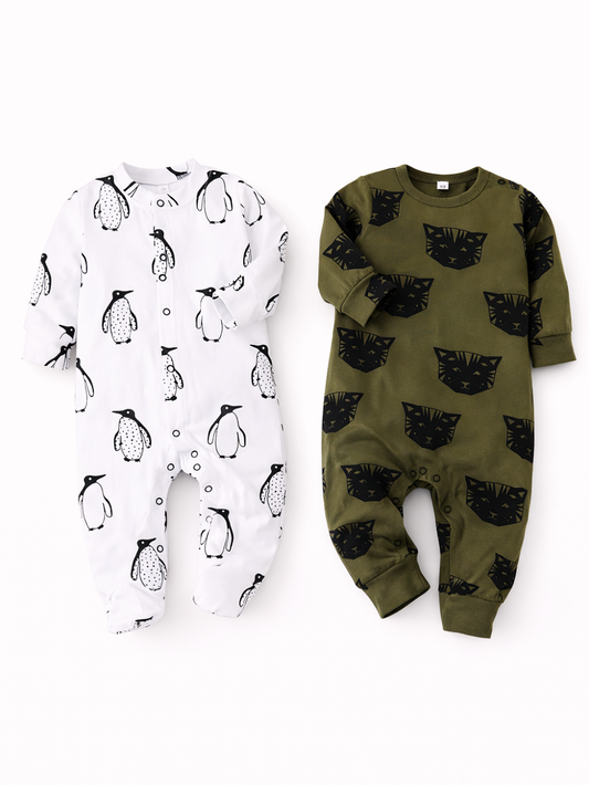 白背景に、ベビー用の長袖ロンパースが2着並んでいる。左は白地にペンギン柄の足つきロンパース、右はカーキ地に黒いネコの顔柄の足なしロンパース。やわらかな影がつき、縫製や生地の質感がはっきり見える。
