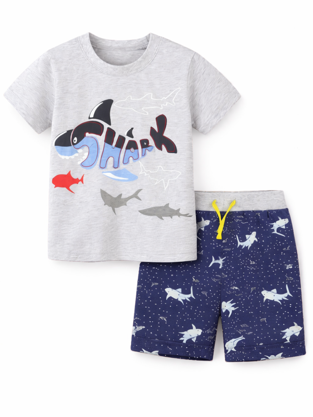 白背景に並べられた子ども用夏の上下セット。杢グレーの半袖Tシャツにサメのイラストと「SHARK」のプリント、ネイビーのショートパンツはサメ柄で、ウエストに黄色のドローコードが付いている。
