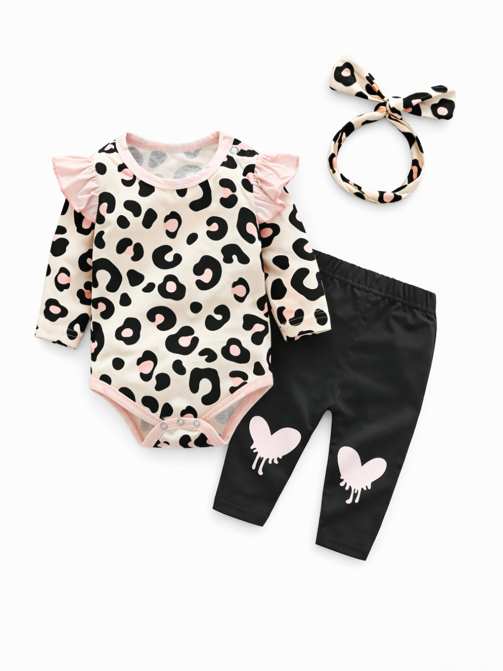 白い背景に、ベビー用の3点セットが平置きで並んでいる。ピンクのフリル付きレオパード柄長袖ロンパース、裾にハート柄が入った黒のレギンス、同柄のリボンヘアバンド。
