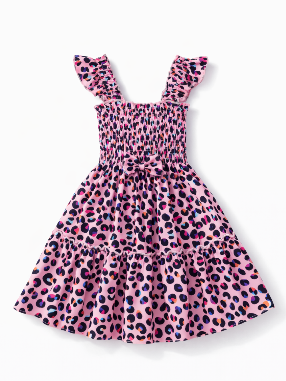 白背景のスタジオで撮影された、ピンクのレオパード柄ティアードワンピース。シャーリング仕様の身頃とフリル付きの肩ストラップ、ウエストの小さなリボンが特徴で、裾は2段のギャザーでふんわり広がっている。
