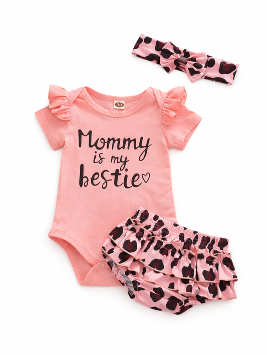 白背景に並べられたベビー用3点セット。ピンクのフリル袖ロンパース（胸元に「Mommy is my bestie」のプリント）、ピンク×ブラックのレオパード柄フリルブルマ、同柄のリボン付きヘアバンドが写っている。
