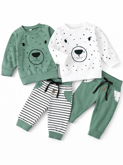 白背景に並べたキッズ用スウェット上下セット2種類。左はグリーンのくま顔プリントトレーナー＋白黒ボーダーのパンツ、右は白地ドット柄のくま顔プリントトレーナー＋グリーンのパンツで、いずれもリブ袖・裾とウエスト紐付き。
