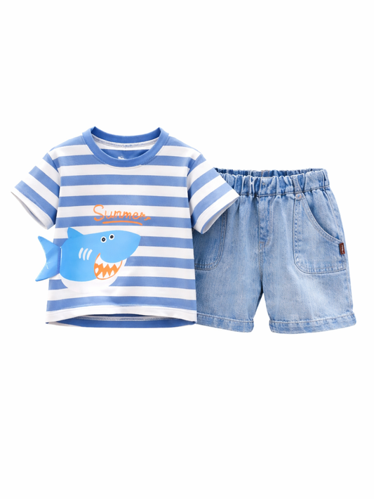 白背景のスタジオで、子ども用の上下セットが並んでいる。青×白のボーダーTシャツにはサメのイラストと「Summer」の文字が入り、隣にライトブルーのデニムショートパンツが配置されている。
