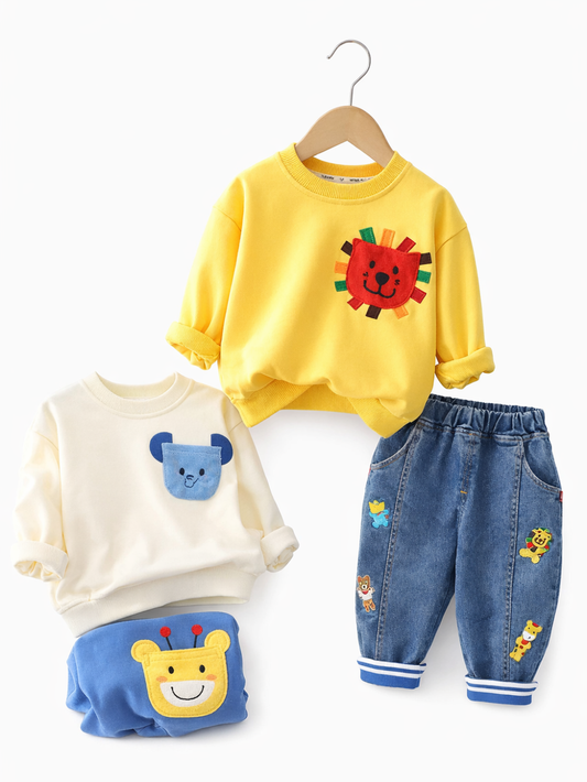 キッズ用の**黄色いスウェット（ライオンのポケット付き）**と**動物ワッペン付きデニムパンツ**のセットが、**真っ白なスタジオ背景**に整えて配置された商品写真。均一な照明で、やわらかな微影が入っています。
