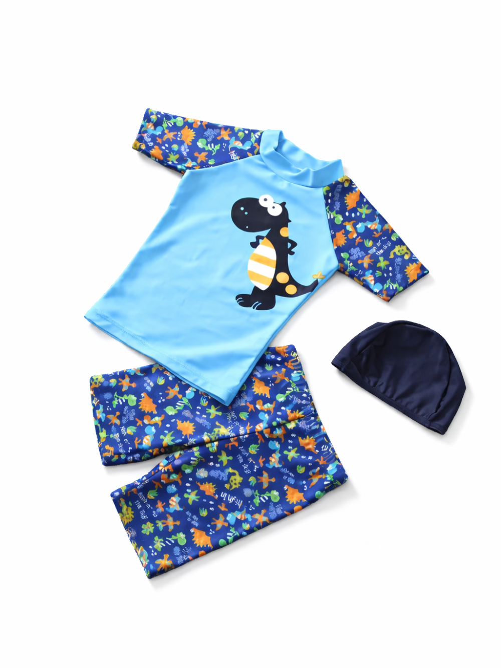 白背景に配置されたキッズ用スイムウェア3点セット。水色の長袖ラッシュガード（恐竜プリント）、同柄のスイムパンツ、ネイビーのスイムキャップがセットになっている。
