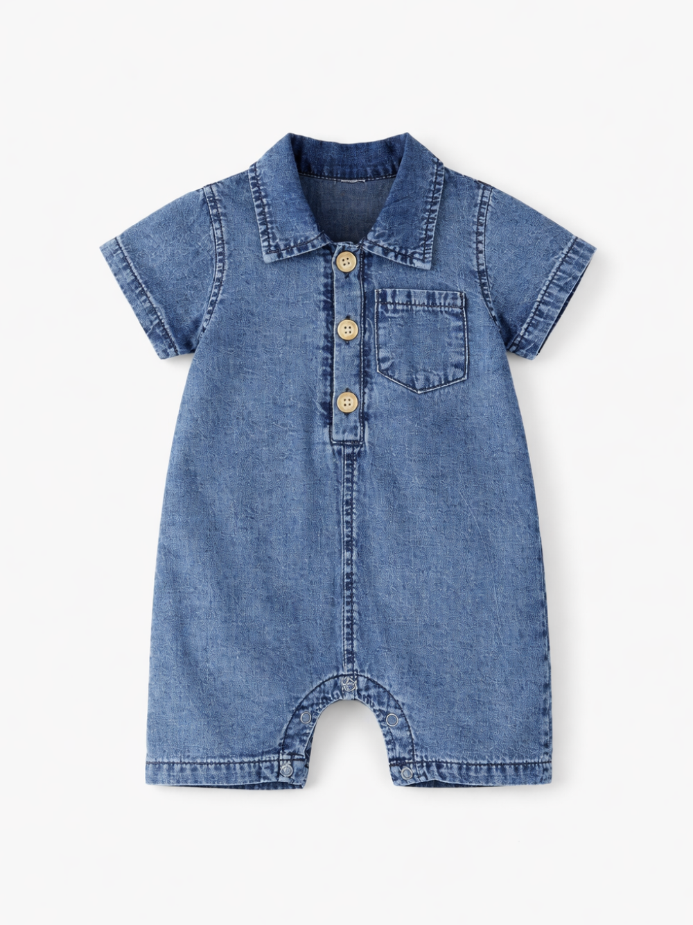 デニム素材のベビー用ロンパース（半袖・襟付き）を、真っ白な背景にフラットレイで配置した商品写真。フロントに木製ボタン3つと胸ポケットがあり、ステッチや生地の質感がはっきり見える。
