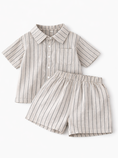 白背景に平置きされた、ベージュ地にネイビーストライプのキッズ半袖シャツとショートパンツの上下セット。
