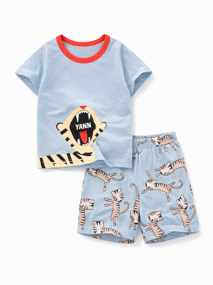水色の半袖Tシャツ（赤い襟・トラの口プリント）と、水色のショートパンツ（トラ柄総柄）の子ども用上下セットを、純白の背景で平置き撮影した商品画像
