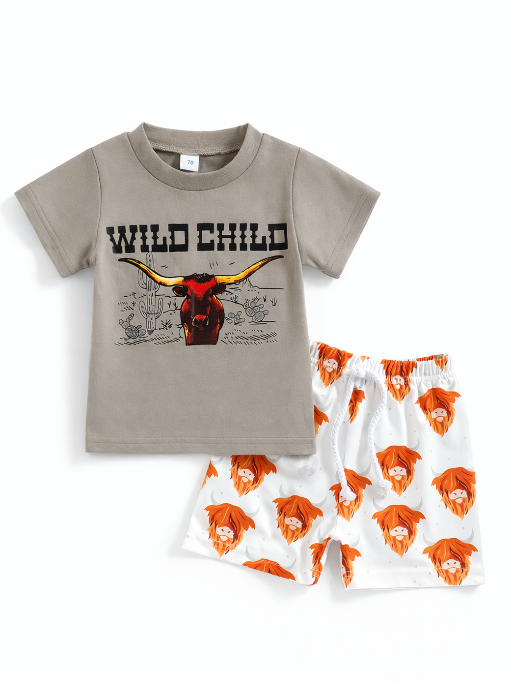 子ども用の半袖Tシャツとショートパンツの2点セット。グレーのTシャツは「WILD CHILD」ロゴとロングホーン（牛）プリント入り。ホワイトのショーツはオレンジ色のハイランド牛の総柄で、ウエストゴム＆ひも付き。白背景のスタジオ撮影で上下を並べて見せている。
