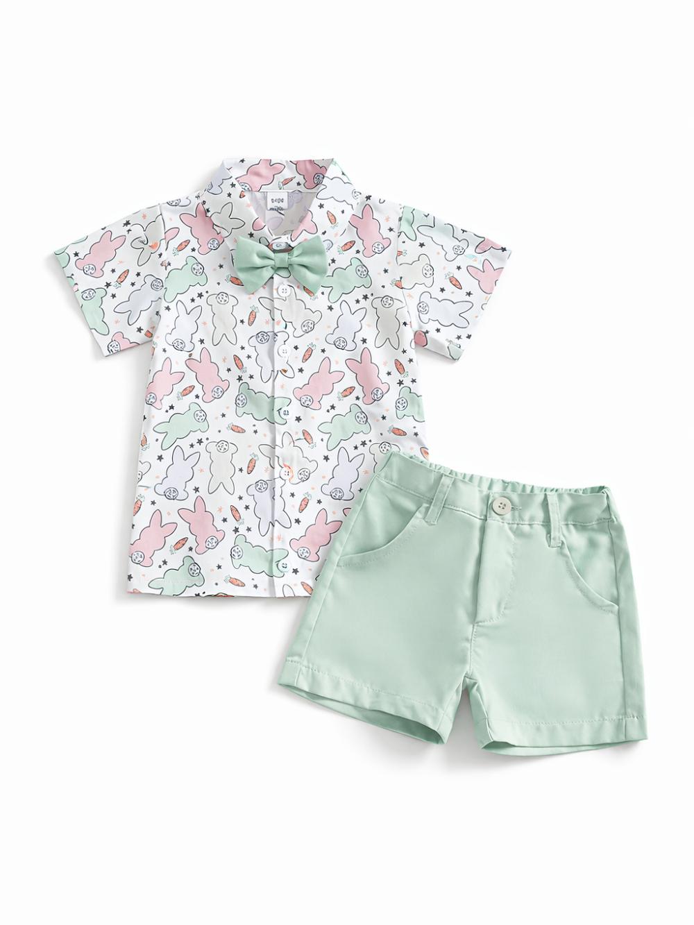 子ども用の半袖シャツとショートパンツの2点セット。白地のシャツはうさぎ柄と小さなモチーフ（にんじんなど）の総柄で、襟付き・前開きボタン・ミント色の蝶ネクタイ付き。ボトムはミントグリーンのショーツで、ポケット付き。白背景のスタジオ撮影で上下を並べて見せている。

