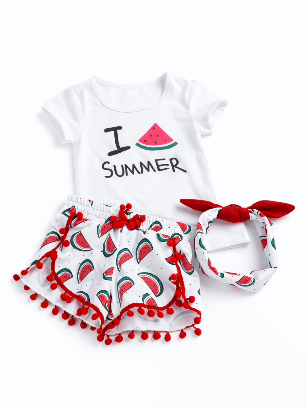 女の子用の半袖Tシャツ・ショートパンツ・ヘアバンドの3点セット。白Tシャツはスイカのイラストと「I SUMMER」プリント入り。白地にスイカ柄のショーツは赤いポンポン付きトリムデザイン。スイカ柄のリボンヘアバンド付き。白背景のスタジオ撮影で3点を並べて見せている。
