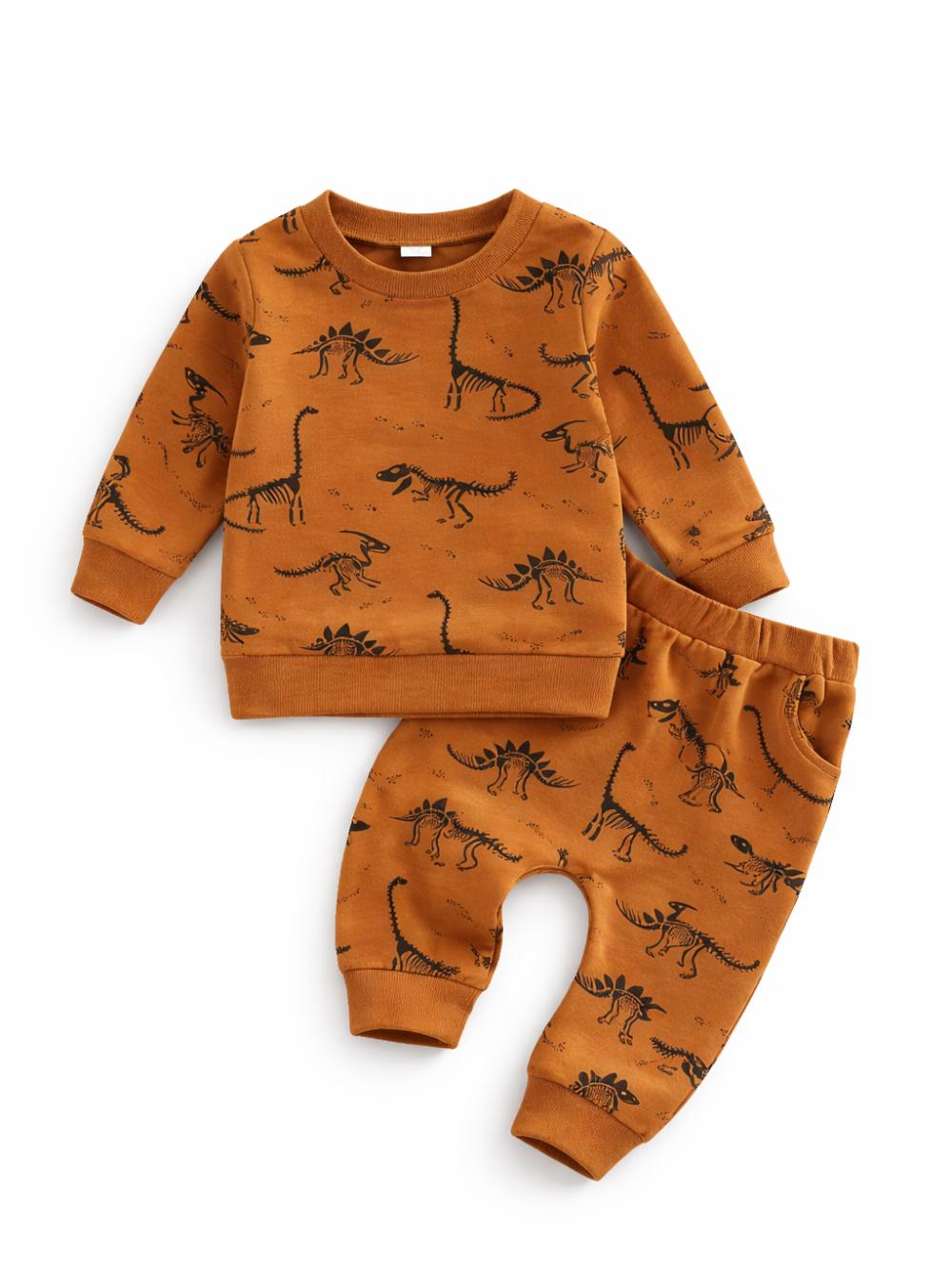 子ども用の長袖トップスとロングパンツの2点セット。キャメルブラウン地に黒の恐竜（骨格）プリント入り。トップスはクルーネックで裾と袖口はリブ仕様、パンツはウエストゴムと裾リブ仕様。白背景のスタジオ撮影で上下を重ねて配置している。

