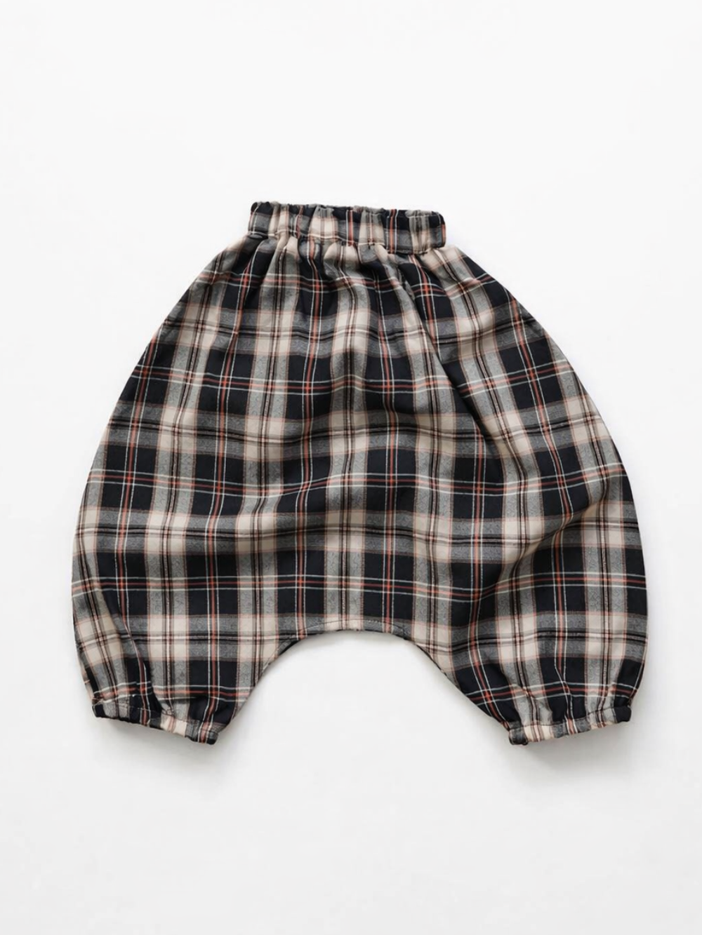 チェック柄のベビーサルエルパンツ。ウエストゴム仕様で、黒・ベージュ・白に細い赤ラインのチェック柄。白背景で正面から平置き撮影。