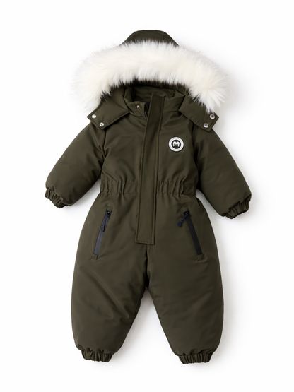 オリーブグリーンの子ども用スノースーツが、真っ白な背景の上に平置きできれいに配置されている。白いファー付きフード、前面のファスナー、袖口と足首のゴム、左右のジップポケット、胸元の丸いワッペンが見える。
