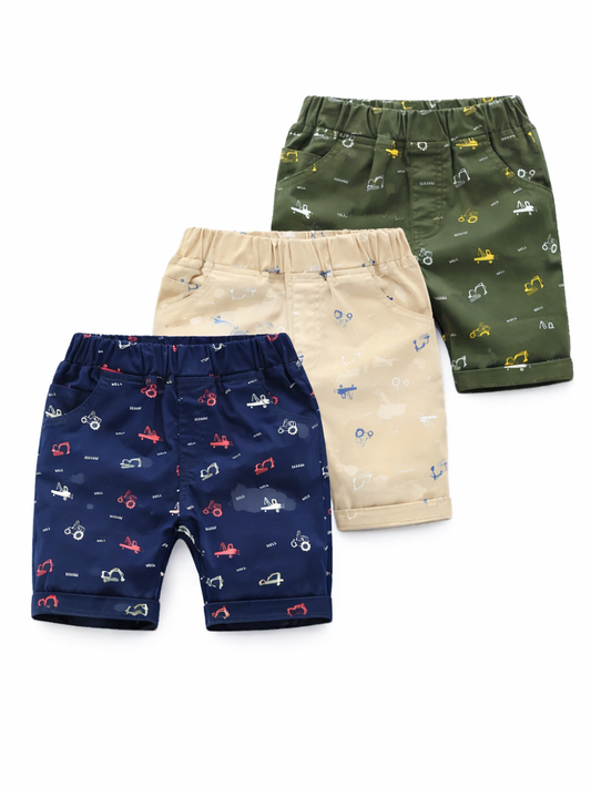 白背景で並べたキッズ用ショートパンツ3点の商品写真。ネイビー・ベージュ・カーキの3色で、乗り物モチーフの総柄プリントとウエストゴム仕様が見える。
