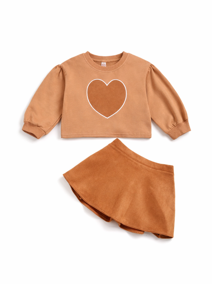 キャメルブラウンの長袖スウェットと、同系色のフレアスカートの女の子用2点セット。胸元にハートモチーフ、袖はふんわりパフ仕様で、白背景のスタジオ撮影で質感と色味がくっきり分かる高精細な商品画像。
