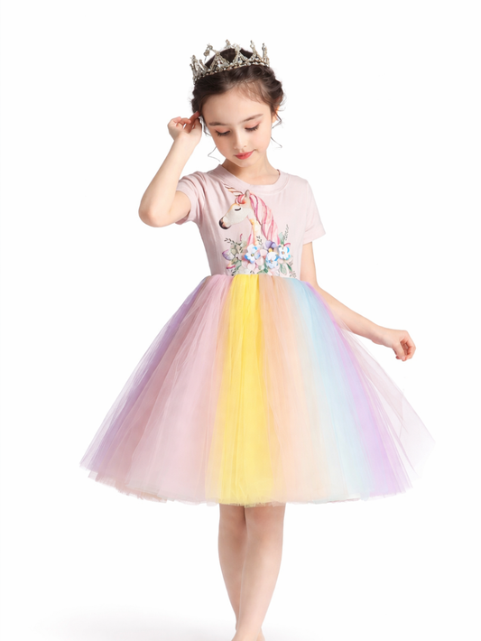王冠をつけた女の子が、ユニコーン柄のトップスとパステルカラーのチュールスカートのドレスを着てポーズをとる、白背景のカタログ風商品画像。
