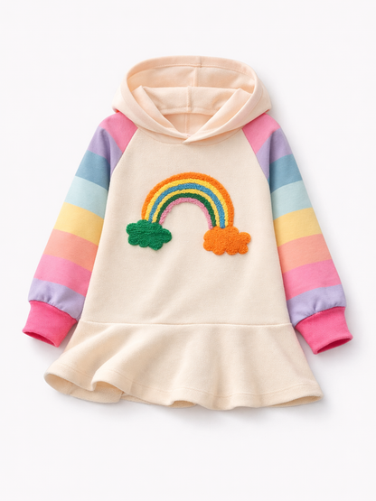純白（#FFFFFF）のスタジオ背景に、子ども用のフード付きワンピースが平置きで写っている。クリーム色のボディに、袖はパステルのボーダー配色で、胸元には立体感のある虹と雲のアップリケが付いている。裾はフレアになっており、全体は均一な照明で質感と色がくっきり見え、下に自然な柔らかい影が入っている。
