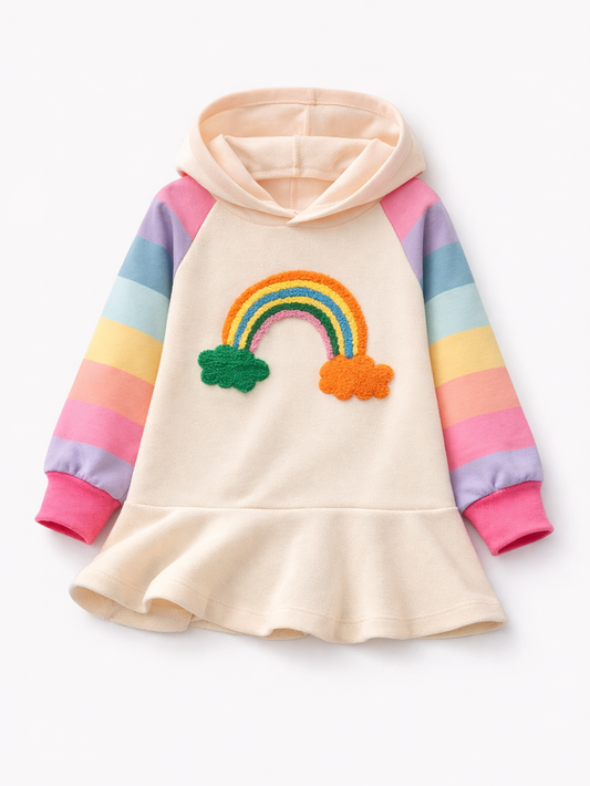 純白（#FFFFFF）のスタジオ背景に、子ども用のフード付きワンピースが平置きで写っている。クリーム色のボディに、袖はパステルのボーダー配色で、胸元には立体感のある虹と雲のアップリケが付いている。裾はフレアになっており、全体は均一な照明で質感と色がくっきり見え、下に自然な柔らかい影が入っている。
