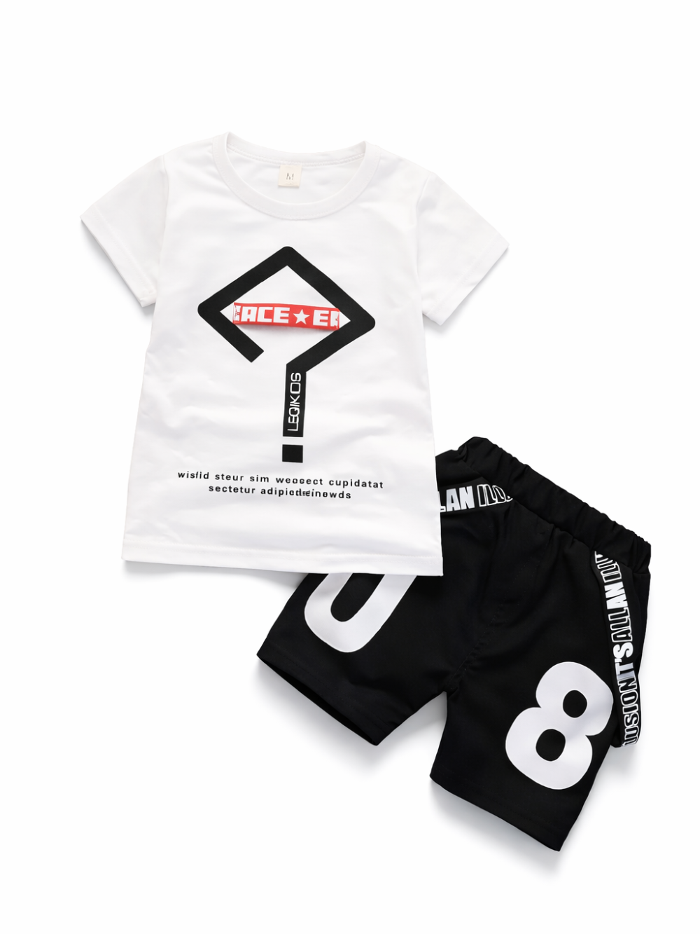 白い半袖Tシャツ（黒×赤のサイン風ロゴプリント）と、黒のショートパンツ（大きな「8」プリント）のキッズ2点セットを、上から撮影した商品画像。Tシャツは左上、パンツは右下に斜め配置。白背景で輪郭がくっきり見える。
