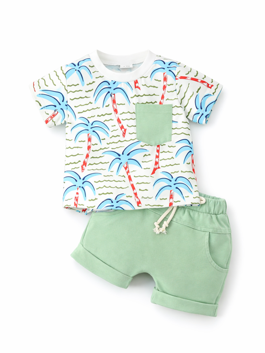 ヤシの木柄プリントの半袖Tシャツと、ミントグリーンのショートパンツのキッズ上下セット。Tシャツは白ベースに青いヤシの葉と赤い幹、右胸に無地のミント色ポケット付き。パンツはウエストゴム＋生成りの紐付きで、裾はロールアップ。白背景に上下を中央配置して撮影した商品画像。
