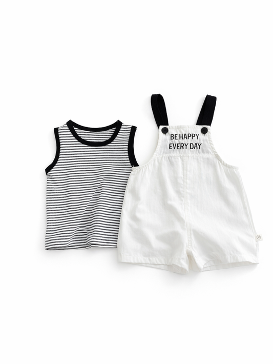 白背景に並べた子ども服の上下セット。左に黒縁の白黒ボーダーのノースリーブトップス、右に黒ストラップ付きの白いサロペットショーツ（胸当てに「BE HAPPY EVERY DAY」のプリント）。
