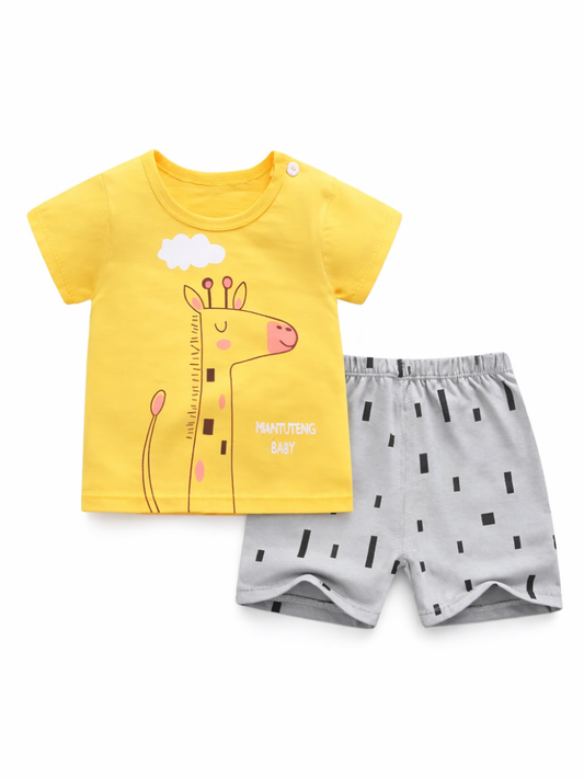 白背景に並べたキッズ用2点セット。黄色の半袖Tシャツにキリンのイラスト、グレーのショートパンツは黒い短いライン柄。明るいスタジオ光で色味がはっきり見える。
