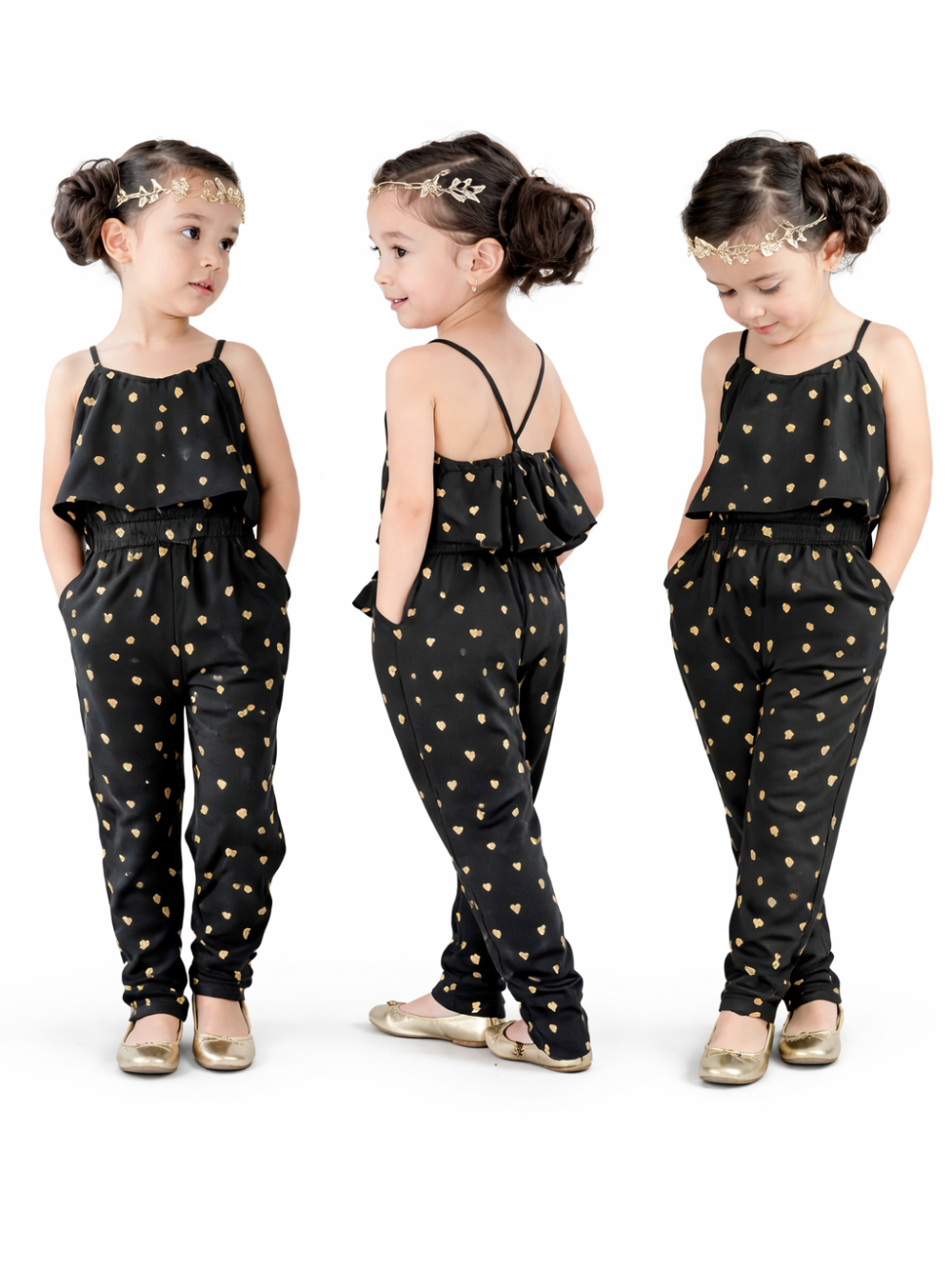 白背景のスタジオで、黒地にゴールドのハート柄が入ったキャミソールタイプのキッズオールインワンを着た女の子。正面・後ろ姿・うつむきの3ポーズでデザインを見せており、髪はお団子、ゴールドのヘッドアクセとゴールドのフラットシューズを合わせている。
