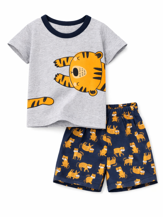 白背景のスタジオ撮影で、キッズ用の半袖Tシャツとショートパンツの2点セット。杢グレーのTシャツには大きなトラのイラストがプリントされ、ネイビーのパンツにはトラ柄が総柄で入っている。
