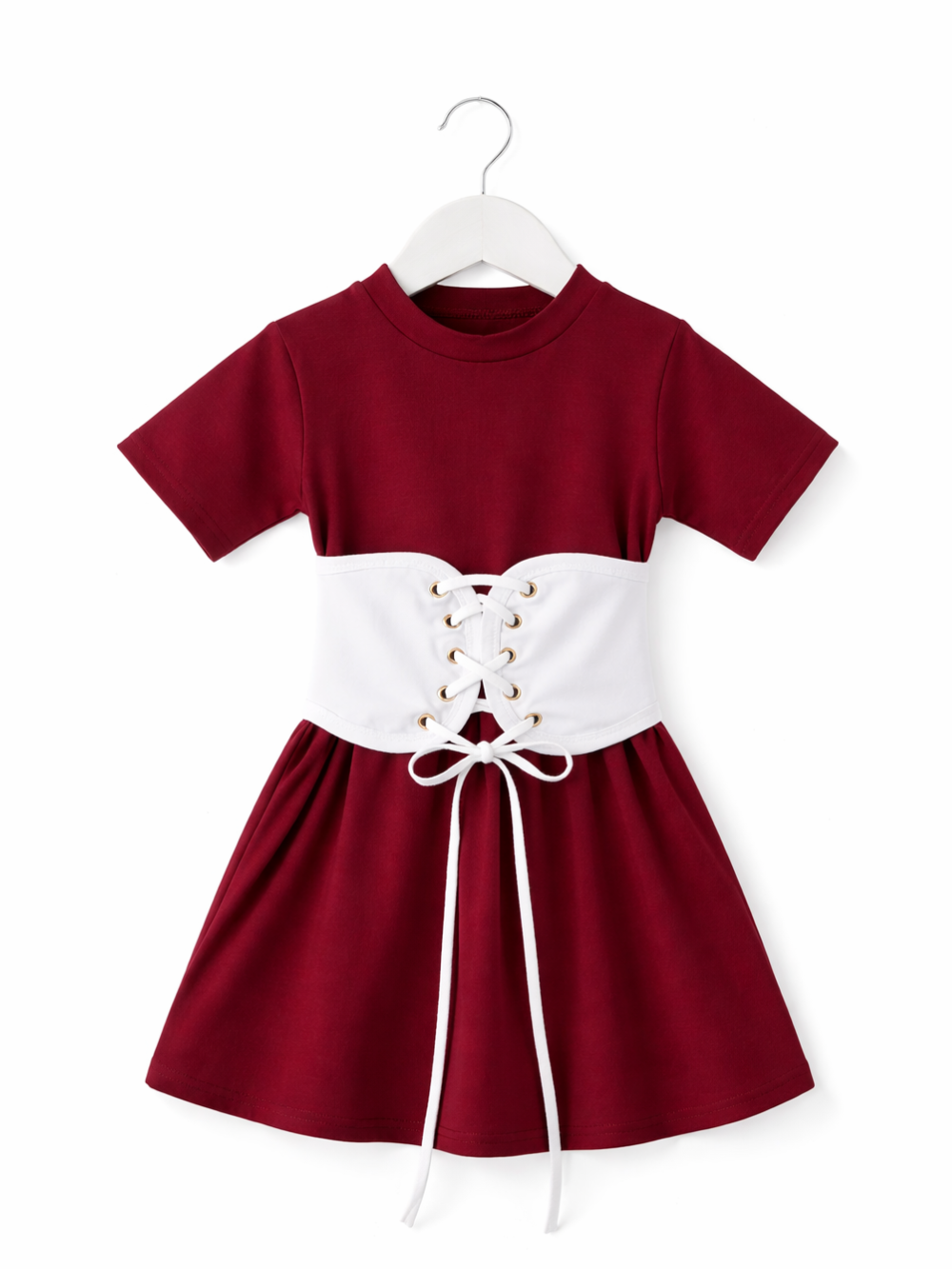 白背景のスタジオ撮影で、ボルドー色の半袖キッズワンピースが白いハンガーに掛けられている。ウエスト部分には白いコルセット風のレースアップベルトが付いており、ゴールドのハトメに白い紐が通されている。
