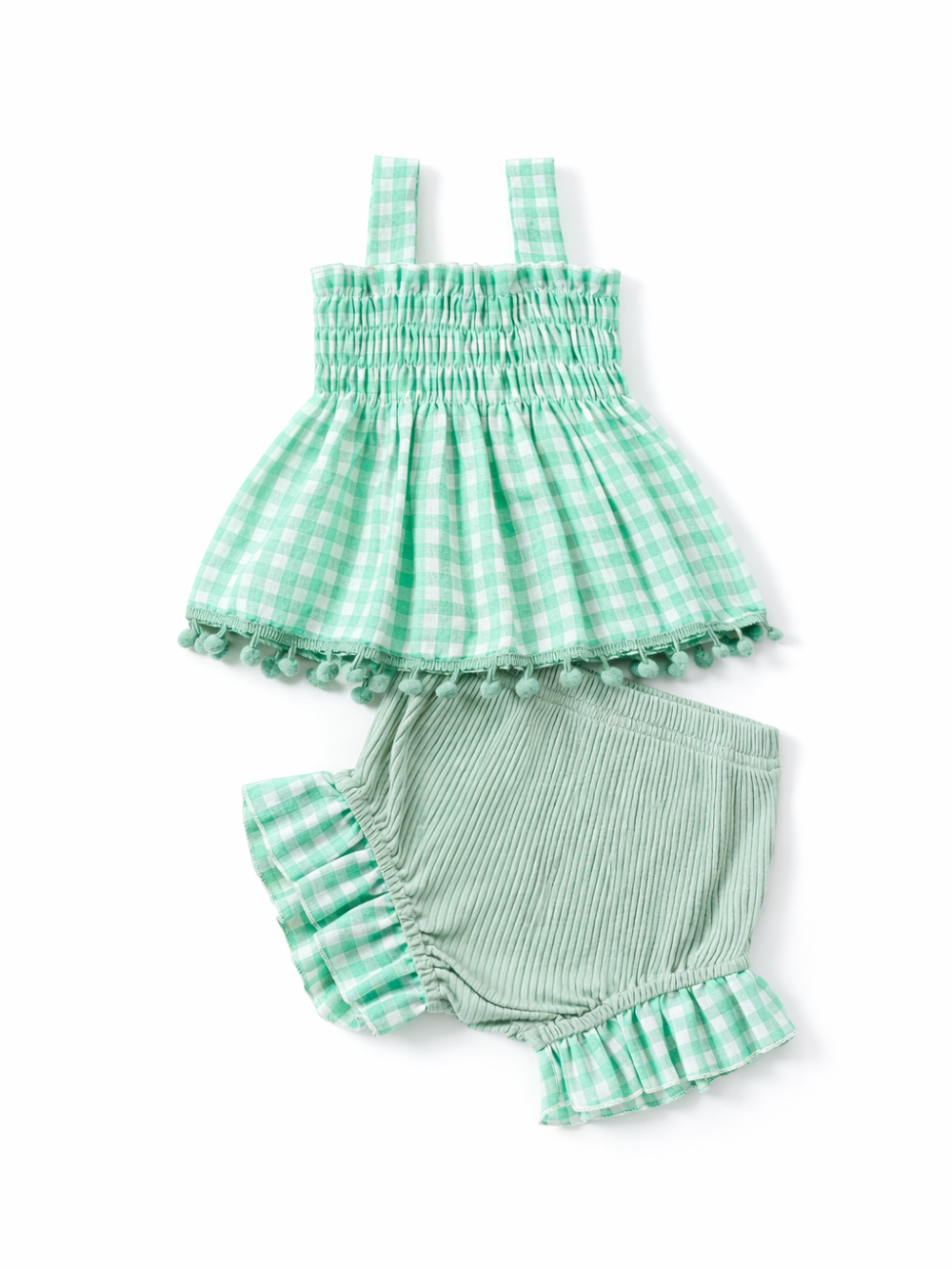 白背景のスタジオ撮影で、グリーンのギンガムチェック柄スモッキングトップスと、セージグリーンのリブ素材ショートパンツのベビー2点セット。トップスは裾にポンポン付きのトリムがあり、パンツはギンガムのフリル裾になっている。
