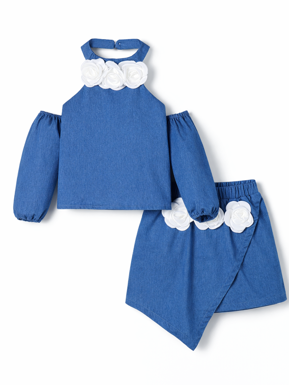白背景に、ミディアムブルーのデニム素材の子ども用ツーピース（オフショルダーのホルターネックトップスとアシンメトリーなスカート）が平置きで写っている。トップスの襟元と袖、スカートのウエストに白いバラのコサージュがあしらわれている。
