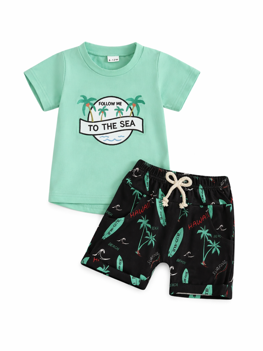 ミントグリーンのキッズ半袖Tシャツと、ヤシの木＆サーフボード柄のブラックショートパンツの2点セット。Tシャツは「FOLLOW ME TO THE SEA」プリント入りで、ウエストは生成りの紐付き。白背景のスタジオ撮影。
