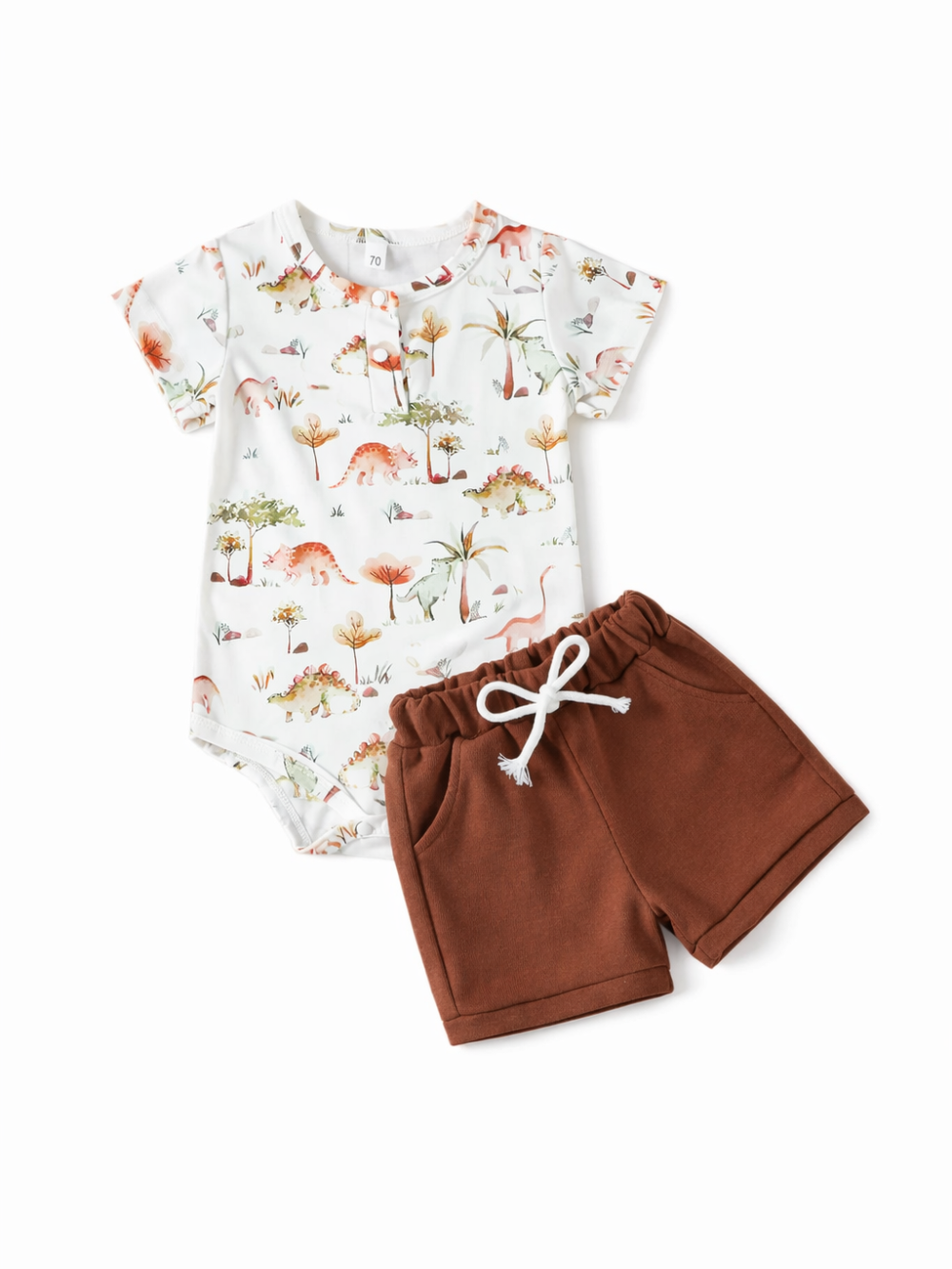 水彩タッチの恐竜＆自然モチーフ柄の半袖ロンパースと、ブラウンのウエストゴムショートパンツの2点セット。パンツは白い紐付きでポケットあり。白背景のスタジオ撮影。
