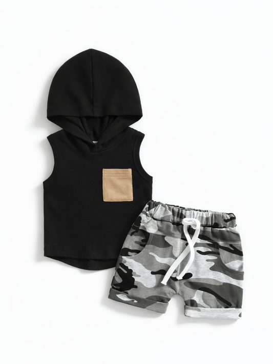 キッズ用の上下2点セット。ブラックのノースリーブフードトップス（胸にベージュポケット付き）と、グレー系カモフラ柄ショートパンツ（白いウエスト紐・ポケット付き）。白背景のスタジオ撮影。
