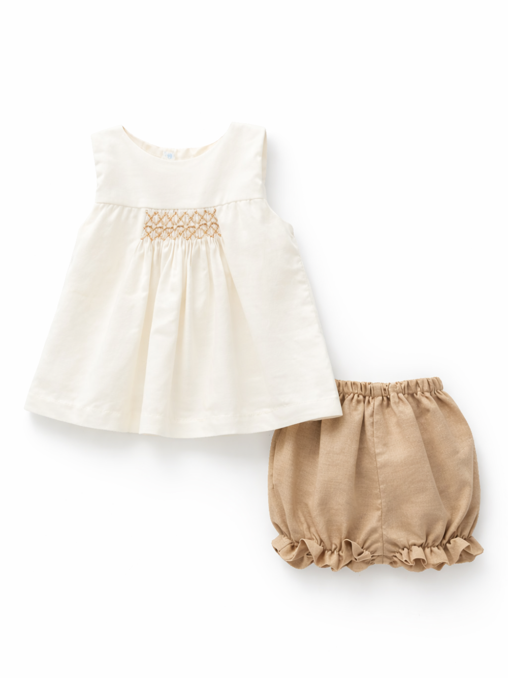ベビー女の子の2点セット。アイボリーのノースリーブチュニック（胸元スモッキング刺繍入り）と、ベージュのフリル裾ブルマ（ウエストゴム）の組み合わせ。白背景のスタジオ撮影。
