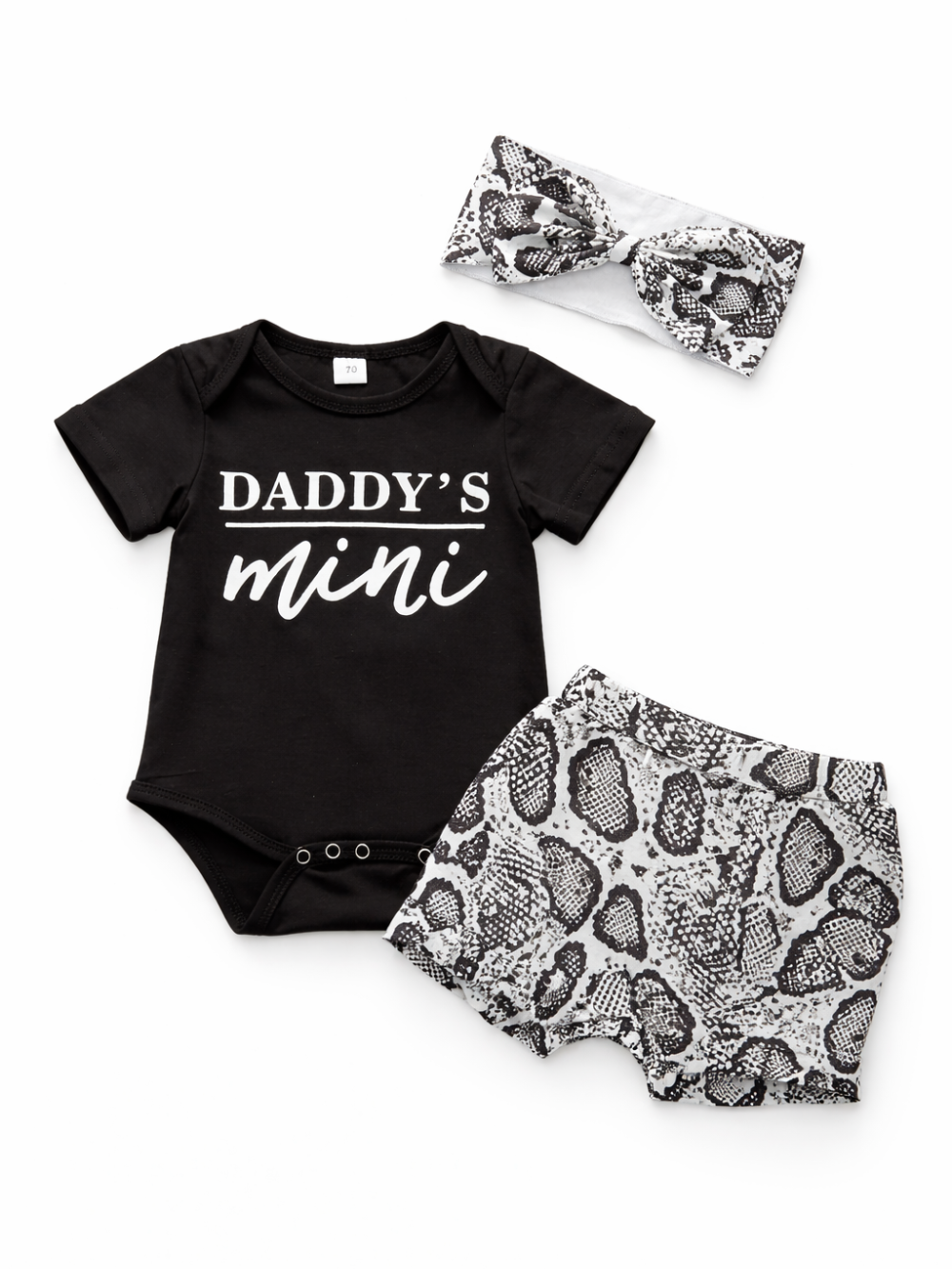 白背景に並べたベビー3点セット。黒の半袖ロンパース（胸元に「DADDY’S mini」プリント）、白黒スネーク柄のブルマ、同柄のリボンヘアバンド。
