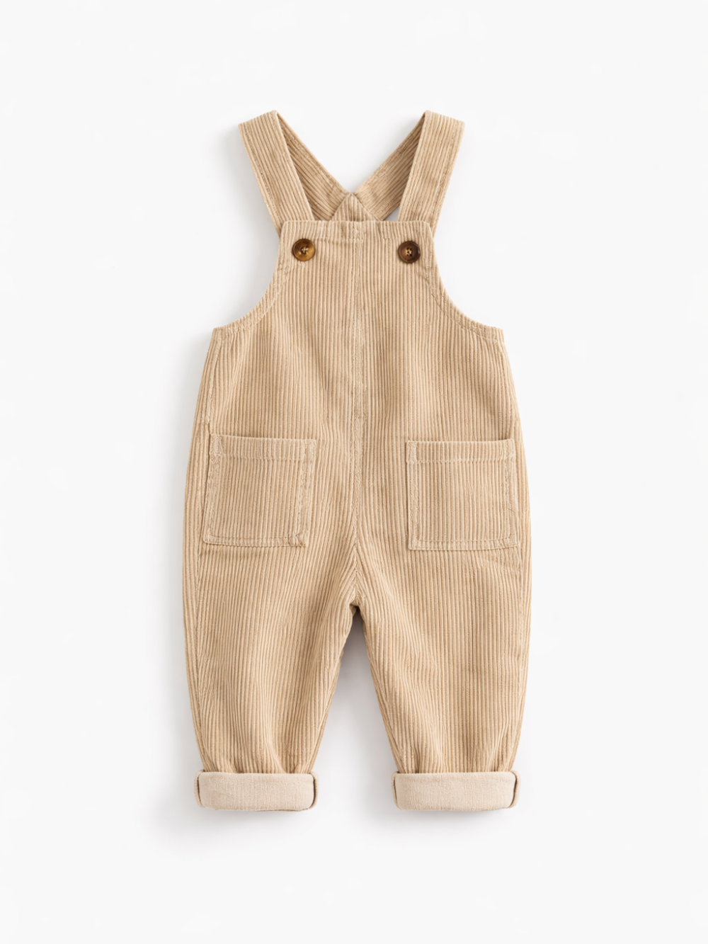 白背景のスタジオ撮影で、ベージュのコーデュロイ素材のベビー用オーバーオールが平置きで写っている。肩ストラップはボタン留めで、前面に大きなポケットが2つあり、裾はロールアップされている。
