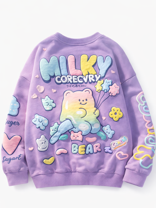 白背景の背面写真。ラベンダー色の子ども用スウェット（長袖）。背中にカラフルな「MILKY」ロゴとクマのキャラクター、グミ風モチーフやハート・花のイラスト入り。
