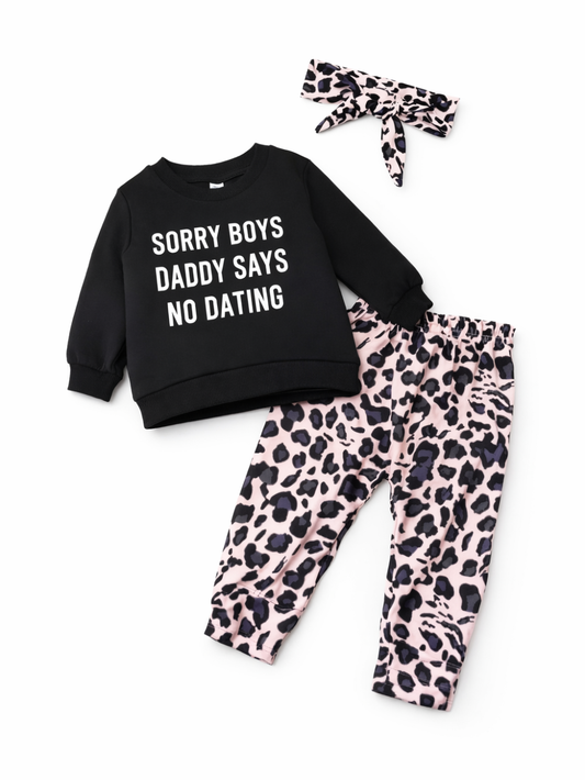 ベビー/キッズ用3点セット。ブラックの長袖スウェット（胸元に白文字プリント入り）、ピンクベースのレオパード柄ロングパンツ、同柄のリボンヘアバンドの組み合わせ。白背景の商品画像。
