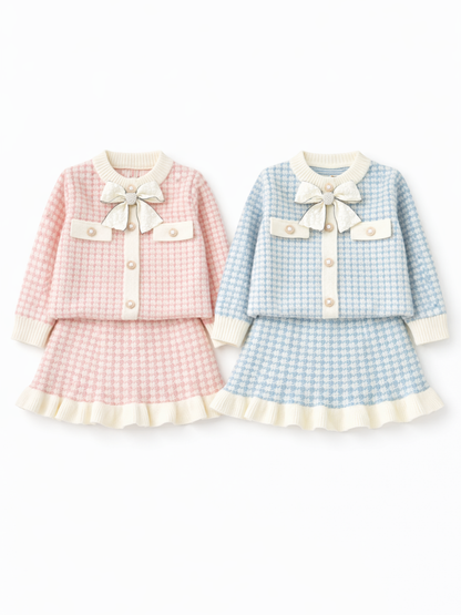 白いスタジオ背景で並べて撮影した、女の子用ツイード風セットアップ2色。ピンク×ホワイトとライトブルー×ホワイトのカーディガン＋スカートセットで、胸元に大きなリボン装飾とパール風ボタン、裾はクリーム色のプリーツフリル仕上げ。2セット全体が見えるカタログ写真。
