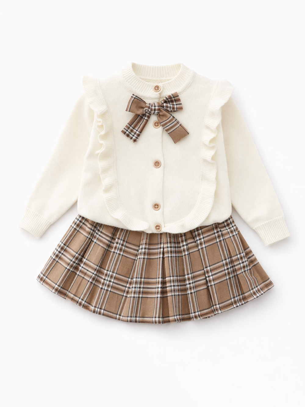 白いスタジオ背景で撮影した、女の子用トップス＋スカートの2点セット。アイボリーのニットカーディガンはフリル縁取りと木調ボタン付きで、首元にブラウンチェックのリボン。ボトムはブラウン系チェック柄のプリーツスカート。セット全体が見えるカタログ写真。
