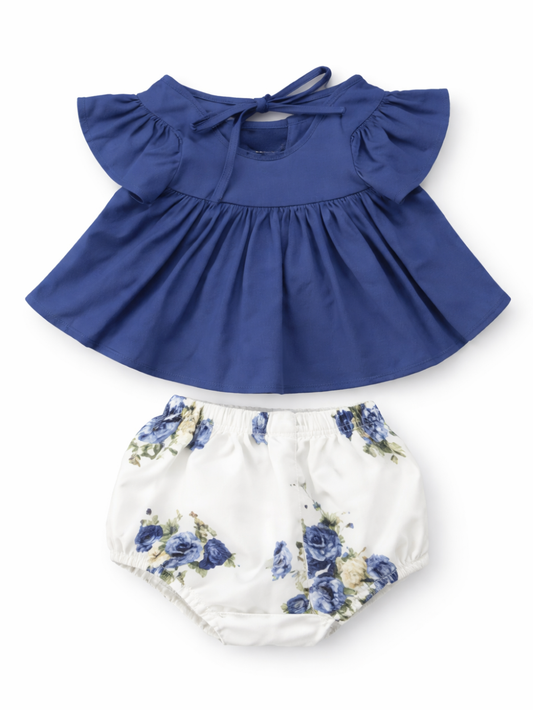 ネイビーのフリル袖トップスと、ブルー系フラワープリントの白いブルマ（かぼちゃパンツ）のベビー用2点セット。フラットレイで全体の形とディテールが分かる商品画像。