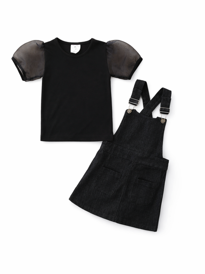 キッズ用ブラックトップス＆デニムジャンパースカートの2点セット商品画像。シアーのパフスリーブ付き黒トップスと、肩ストラップ付きのダークデニムジャンパースカートを白背景で並べたカタログ写真。