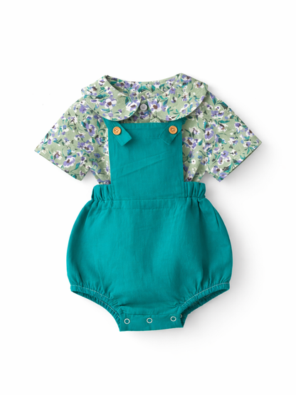 ベビー女の子用の重ね着風コーディネート商品画像。花柄の丸襟ブラウスにエメラルドグリーンのサロペットロンパースを合わせたデザインを、白背景で撮影した上品なカタログ写真。