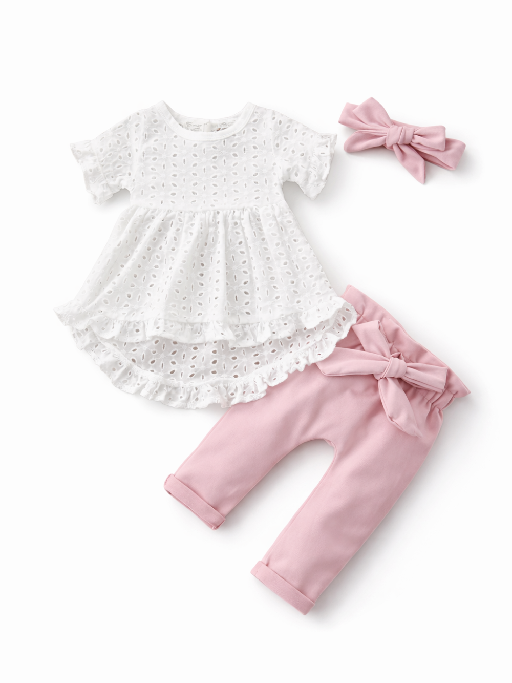 ベビー女の子用の3点セット商品画像。白のアイレットレースチュニック、ピンクのリボン付きパンツ、同色のヘアバンドを白背景で並べたカタログ写真。