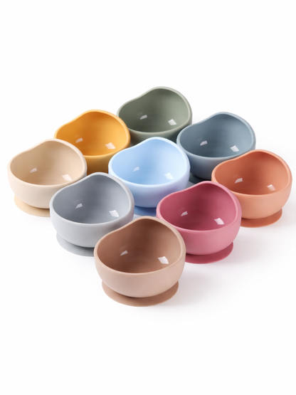 白背景に並べたベビー用シリコン吸盤ボウル9点の製品画像。ベージュ、マスタード、グリーン、ブルー、ピンクなどのくすみカラーを揃えた、丸みのある波型デザインのセット。