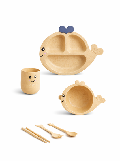 クジラ形ベビー食器セット（砂目ベージュ×ブルー）にこ顔の仕切りプレートとクジラボウル、カップ、しっぽ先端の箸・スプーン・フォークを並べたおうち離乳食の食卓シーン