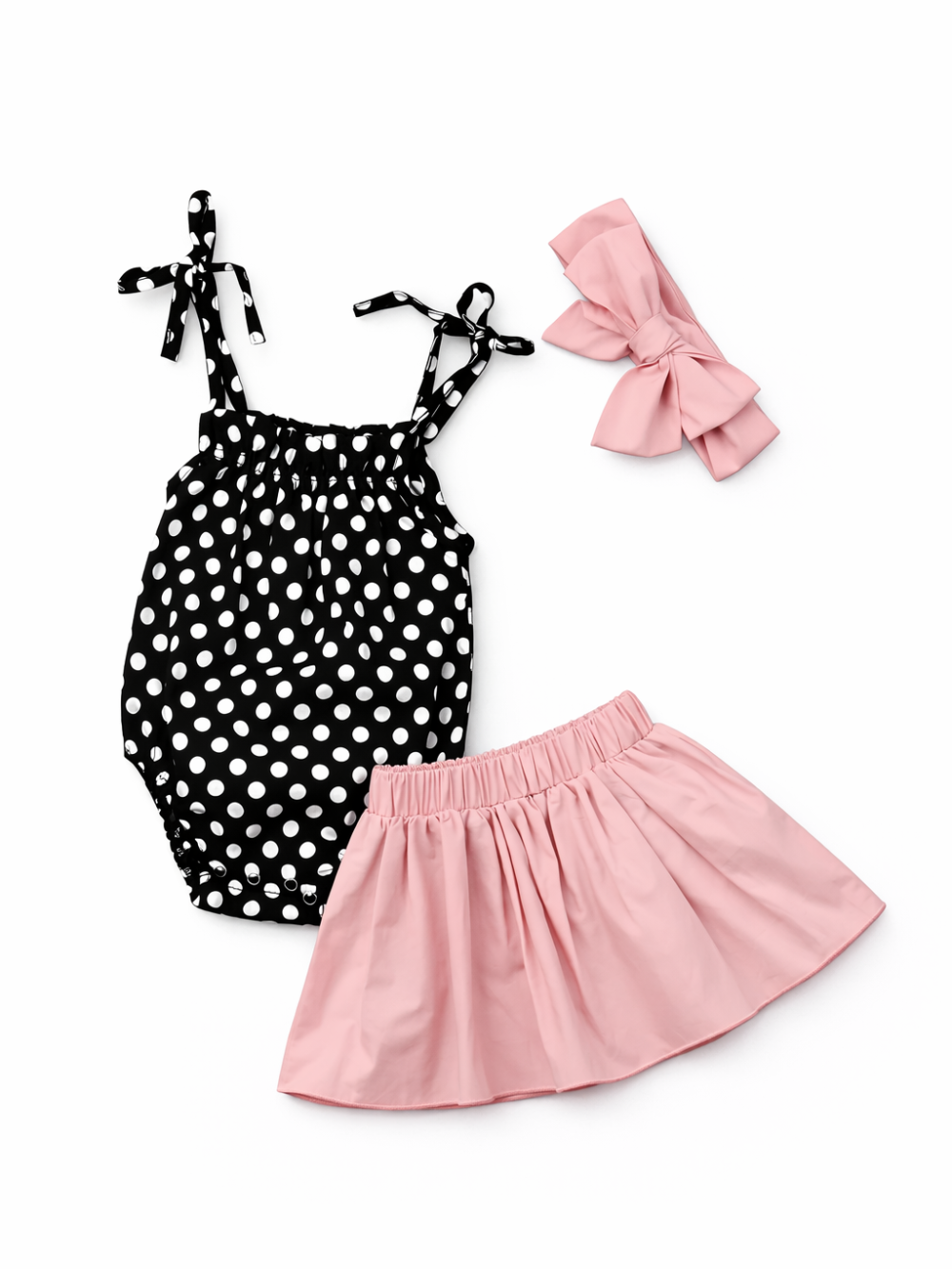 白背景の女の子用3点セット商品写真。黒×白ドット柄のキャミソールロンパース、ピンクのフレアスカート、ピンクのリボンヘアバンドがセットになっている。
